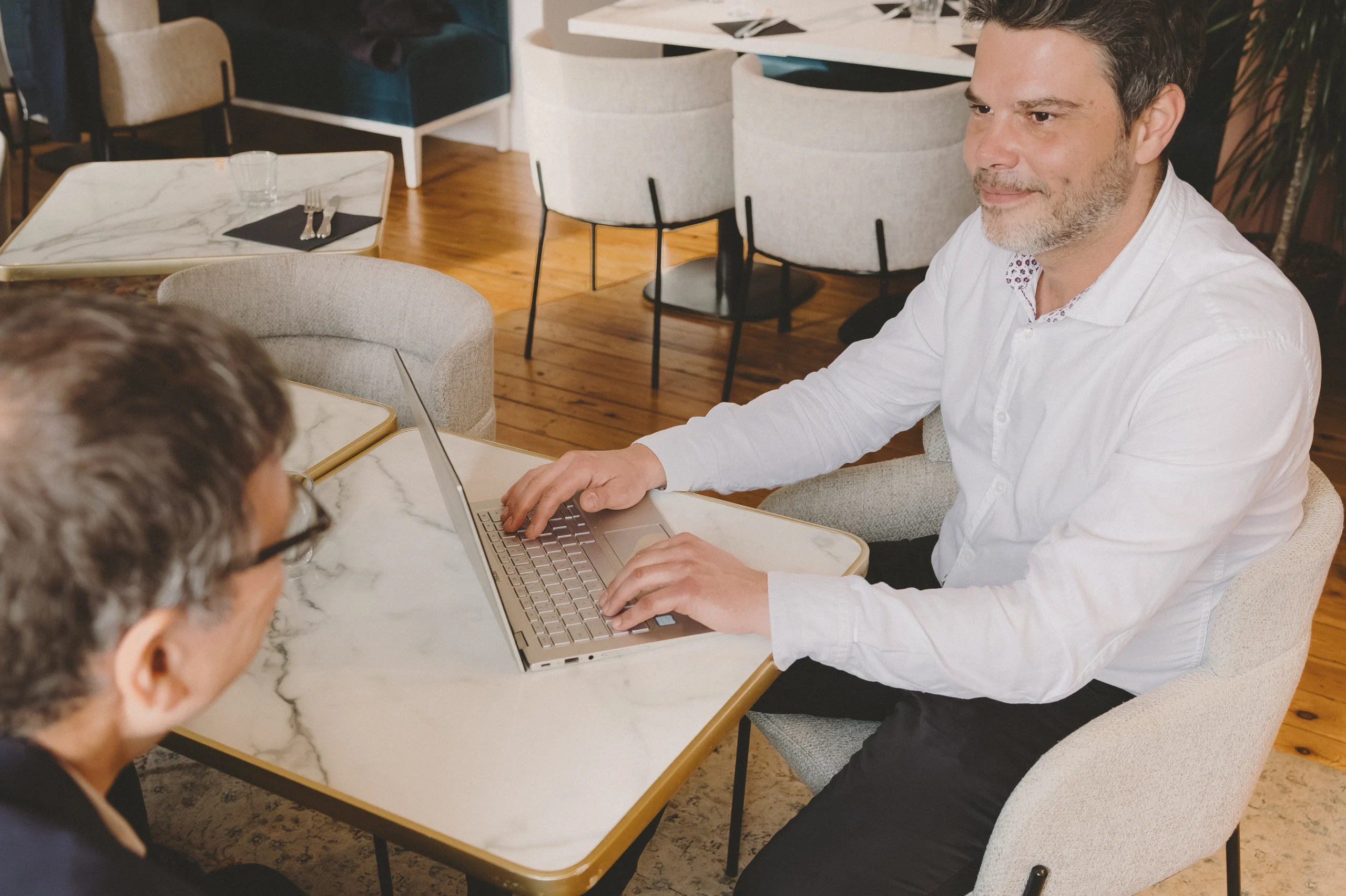 Courtier CL Courtage souriant en pleine discussion avec un client lors d'un rendez-vous de simulation de financement sur ordinateur portable.