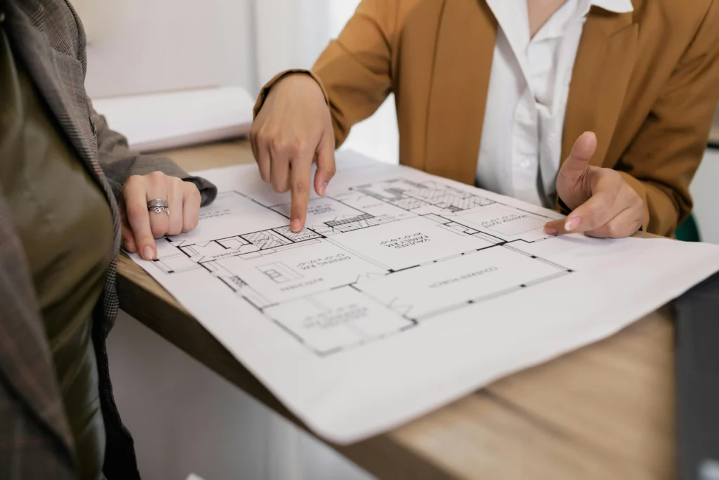 Clients et courtier à Betton étudiant un plan de maison pour définir le budget d'une construction ou d'une rénovation