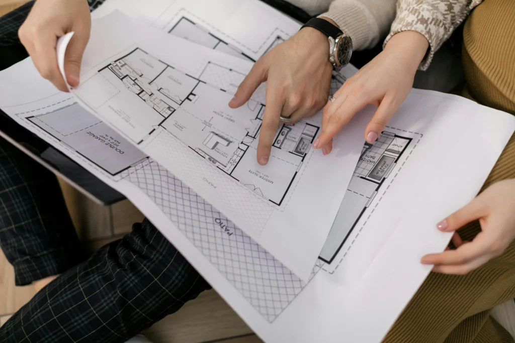 Couple analysant les plans d'une maison avec leur courtier à Chartres-de-Bretagne pour valider le budget de construction