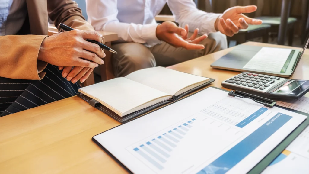 Courtier analysant des courbes de taux et un plan de financement avec ses clients lors d'un rendez-vous à Elven