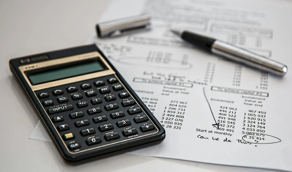 Calculatrice financière et notes manuscrites, illustrant le travail d'optimisation de taux et de montage de prêt réalisé par votre courtier à Pacé