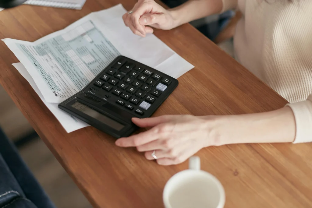 Mains d'une courtière CL Courtage à Rennes utilisant une calculatrice pour analyser des documents financiers et déterminer une capacité d'emprunt