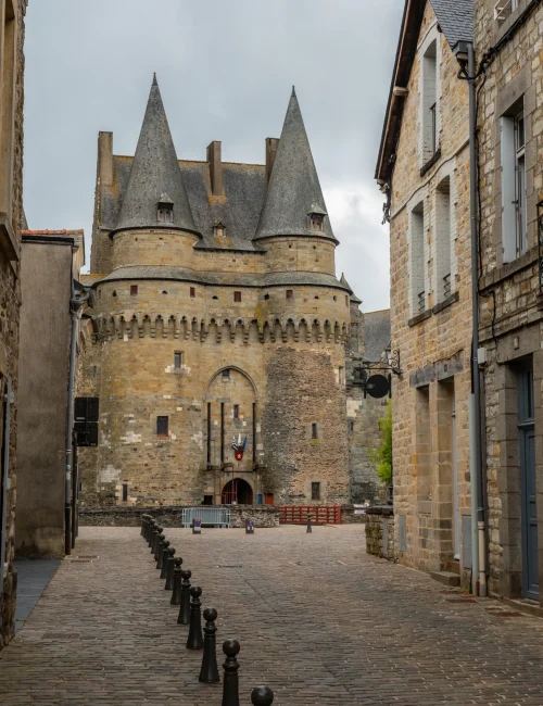 Vue d'une rue pavée menant au Château de Vitré, illustrant la proximité de votre courtier Vitré avec le marché immobilier du centre-ville